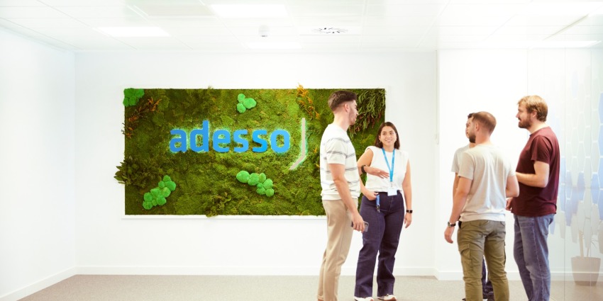 Menschen stehen vor adesso-Logo